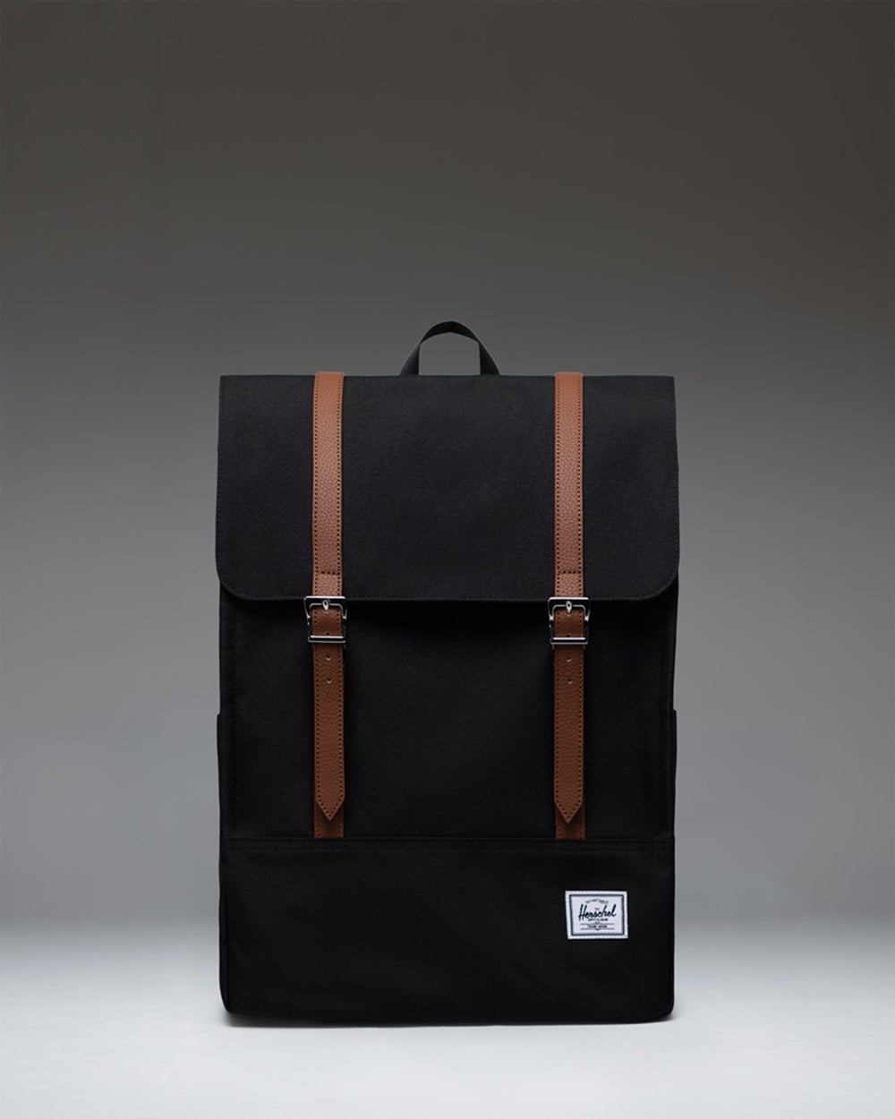Herschel Survey Backpack in black. Front view showing clean design with dual straps and signature logo patch.