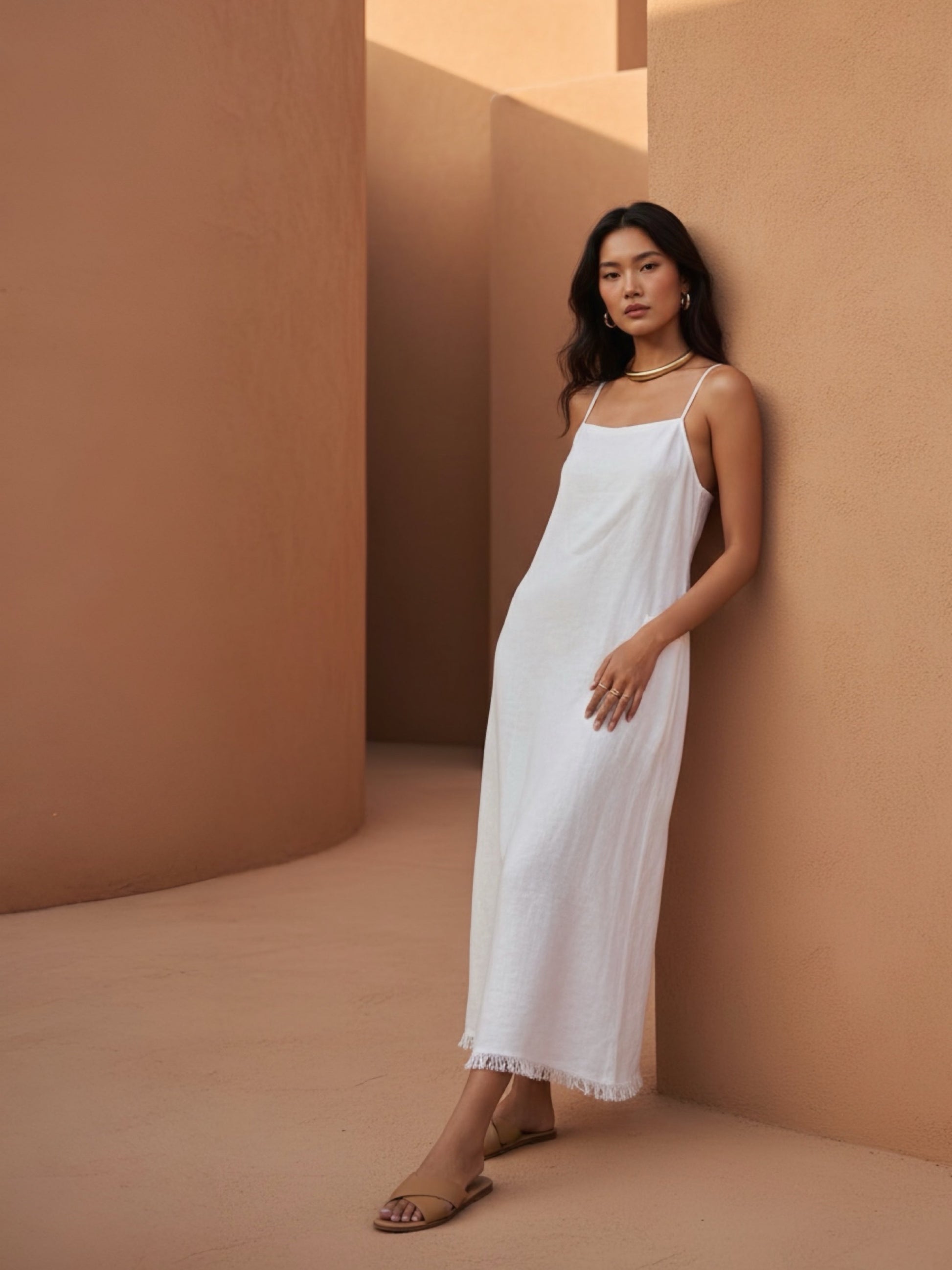 Model wearing white linen slip dress against the wall – minimalist summer look with natural linen fabric- perfect