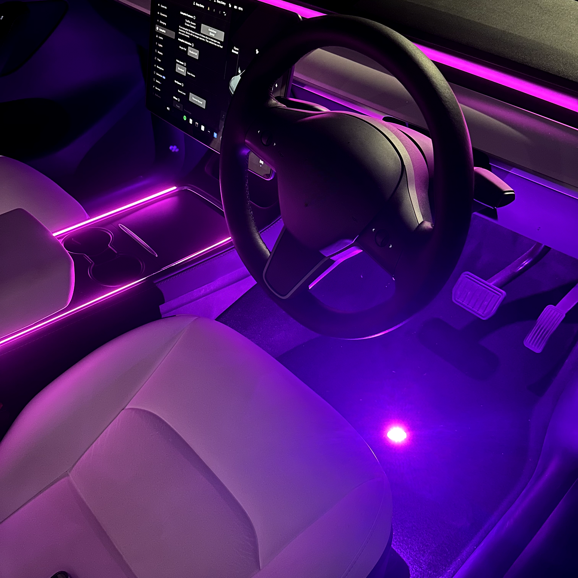An image showing a car interior with LED lights in purple, highlighting the footwell and dashboard area.