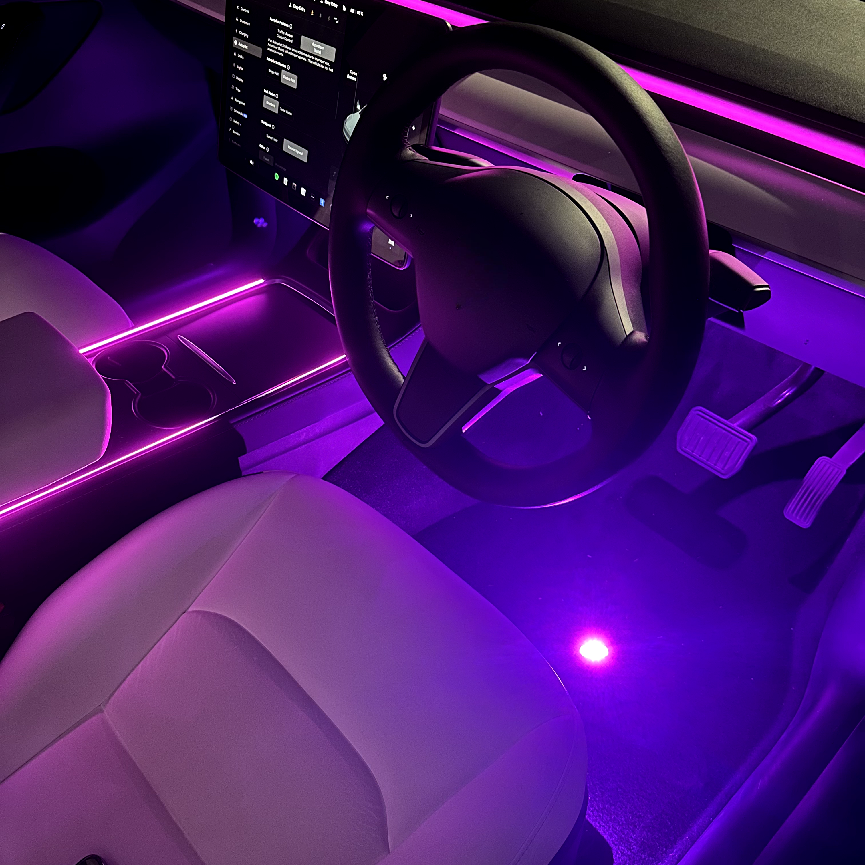 An image showing a car interior with LED lights in purple, highlighting the footwell and dashboard area.