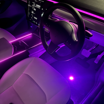 An image showing a car interior with LED lights in purple, highlighting the footwell and dashboard area.