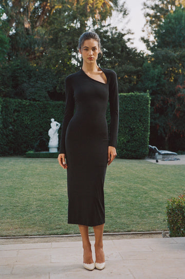 Black Celia full-length long-sleeve dress with a front cutout slit at the neck, worn by a model outdoors.